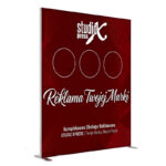 Fotografia wolnostojącego, bordowego kasetonu reklamowego. Na górze logo "studio XPRESS" i trzy puste okręgi. W środku duże białe ozdobne hasło "Reklama Twojej Marki". Na dole mniejszy tekst: "Kompleksowa Obsługa Reklamowa STUDIO XPRESS | Twoja Marka, Nasza Pasja". Prosty metalowy stelaż na dole.